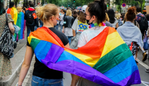 two gen z lgbtq+ women draped in a pride flag