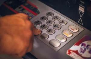 A hand entering numbers on a ATM keypad