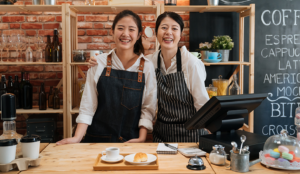 Two Asian women in aprons standing at their kitchen counter