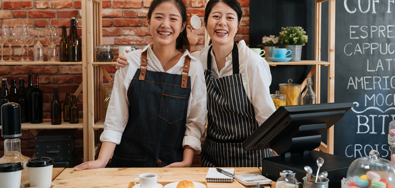 Two Asian women in aprons standing at their kitchen counter