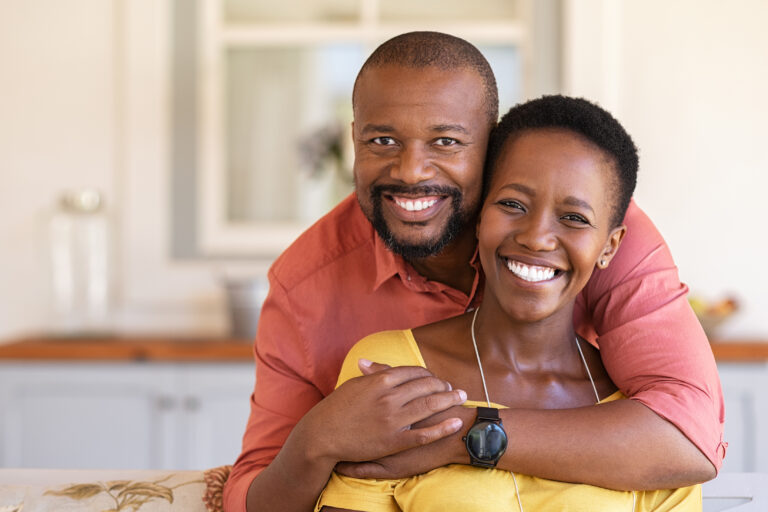 Smiling Black couple embracing and looking at the camera