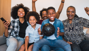 Black family watching a soccer game on their couch