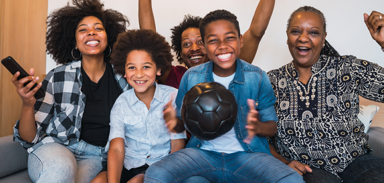 Black family watching a soccer game on their couch