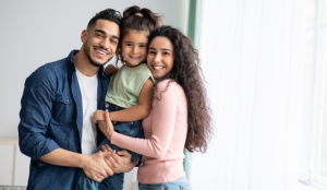 Young Hispanic couple embracing their young daughter