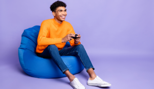 Young black man sitting on a bean bag playing a video game