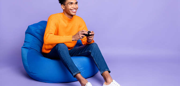 Young black man sitting on a bean bag playing a video game