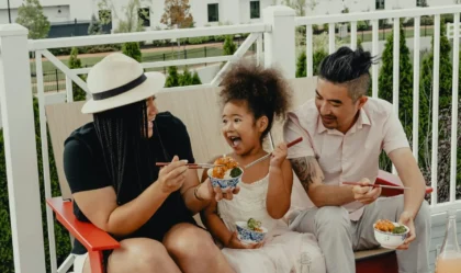 Multicultural family enjoying food outside on a bench